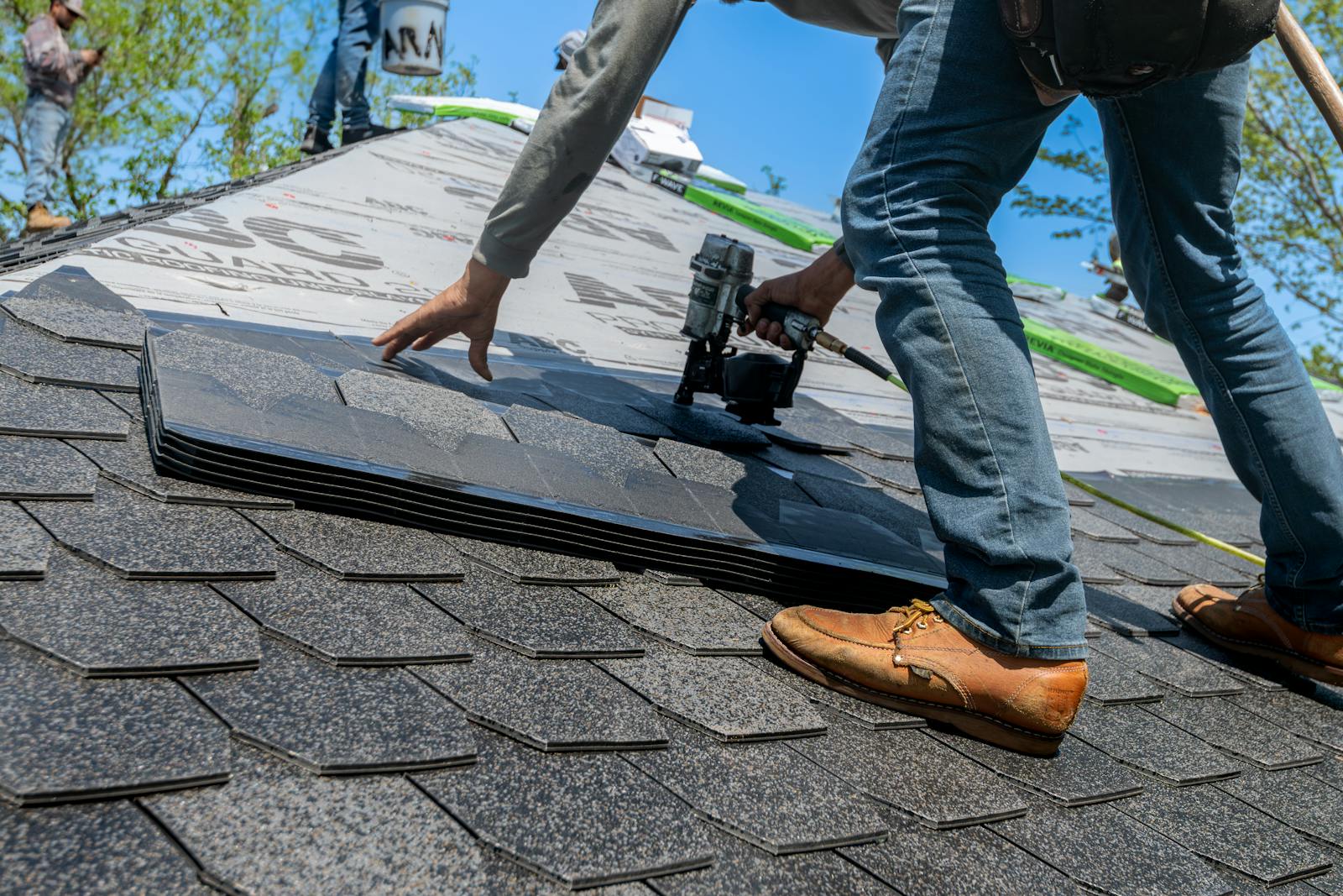 Photo by Ryan Stephens Roofer using nail gun for shingle installation on residential roof.