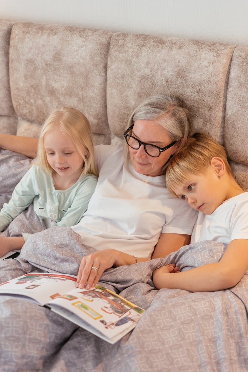 A loving grandmother reads to her grandchildren tucked in bed together.